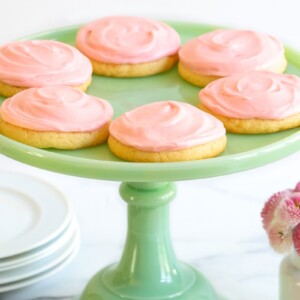 Horizontal photo of a batch of Copycat Crumbl Sugar Cookies on a jade green pedestal serving plate.