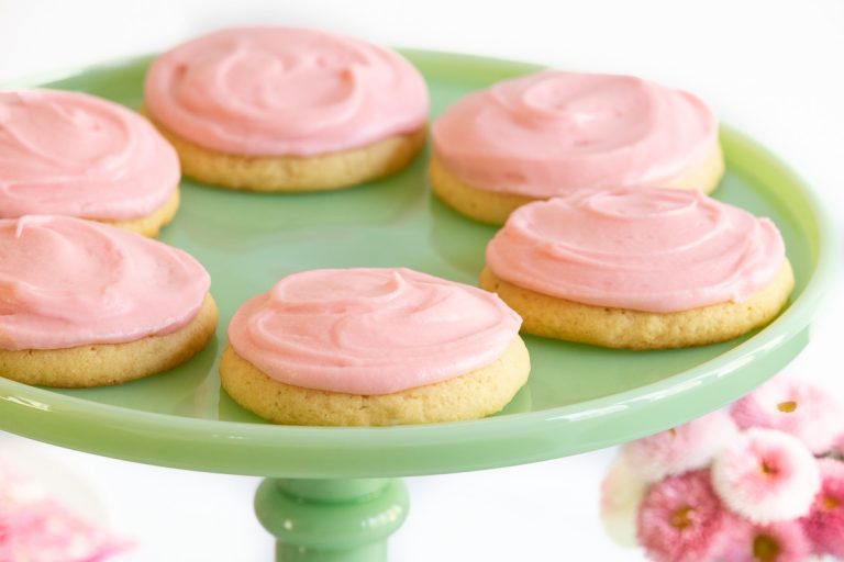 Horizontal closeup photo of a batch of Copycat Crumbl Sugar Cookies on a pale green marble pedestal plate.