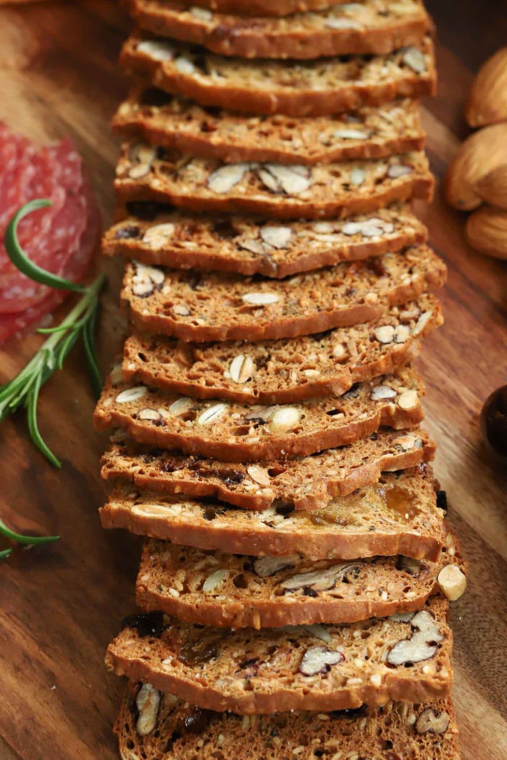 Vertical closeup photo of Copycat Rosemary Pecan Raincoast Crackers on a wooden cheeseboard.