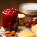 Vertical picture of Cranberry Clementine Conserves in a glass jar with cheese and nuts