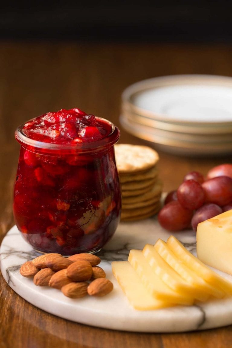 Vertical picture of Cranberry Clementine Conserves in a glass jar with cheese and nuts