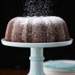 Vertical picture of carrot bundt cake with powdered sugar on a blue cake stand