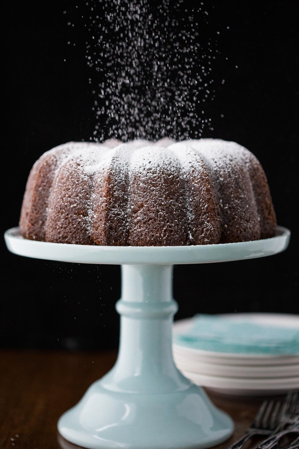 Vertical picture of carrot bundt cake with powdered sugar on a blue cake stand