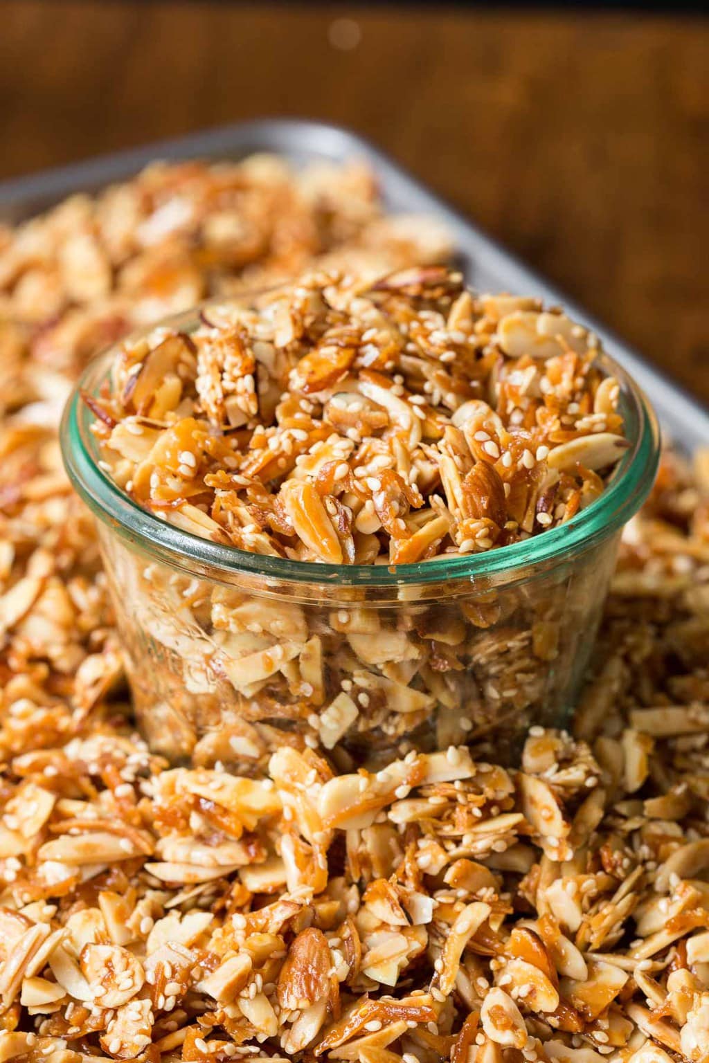 Close-up photo of a Weck jar full of Double Almond Paleo Granola in the middle of a sheet pan of granola.