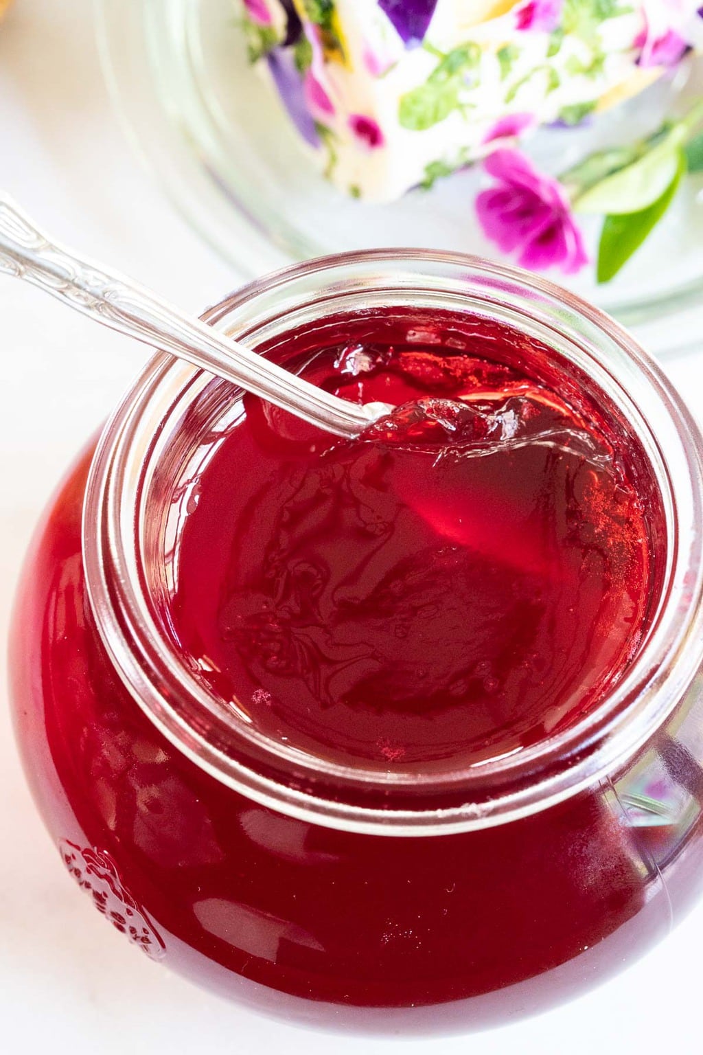 Vertical photo of a glass jar of Easy Blackberry Jelly with a spoon.