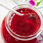 Closeup vertical photo of a glass jar of Easy Blackberry Jelly with a custom printed label on the lid.