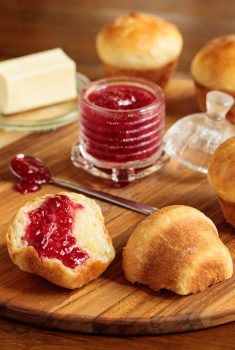 Vertical picture of Brioche Dinner Rolls with jam and butter