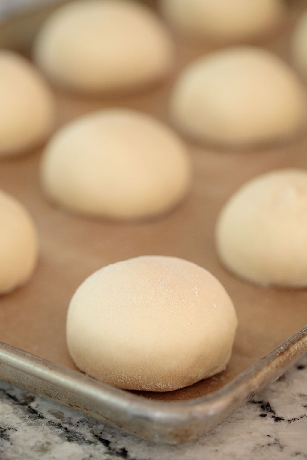 Photo of a parchment covered baking pan filled with Easy Buttermilk Brioche Buns just before baking.