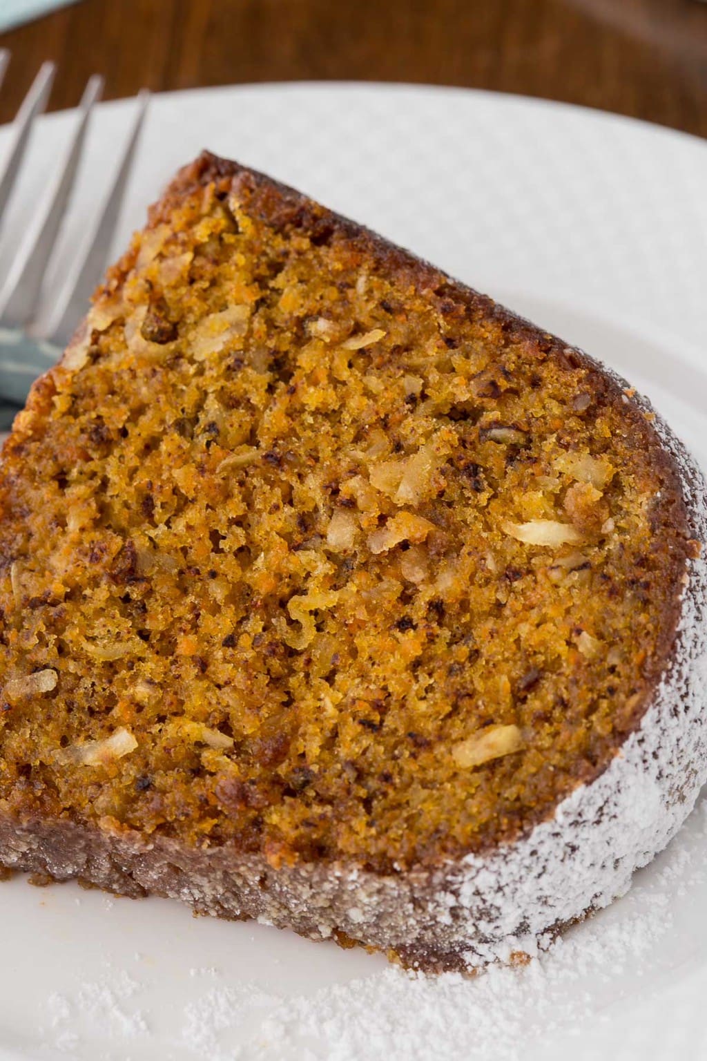 Closeup photo of a slice of Easy Carrot Cake with Buttermilk Glaze on a white serving plate.