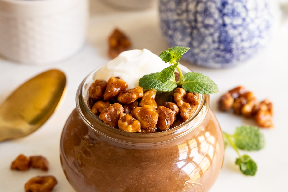 Horizontal closeup photo of Easy Chocolate Budino with Candied Maple Walnuts in a Weck jar on a white countertop.