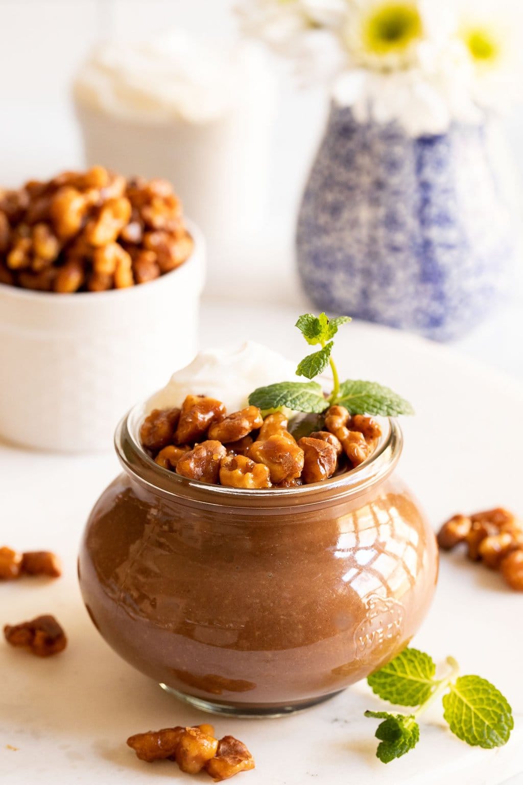 Vertical photo of Chocolate Budino in a glass Weck jar garnished with Candied Maple Walnuts.