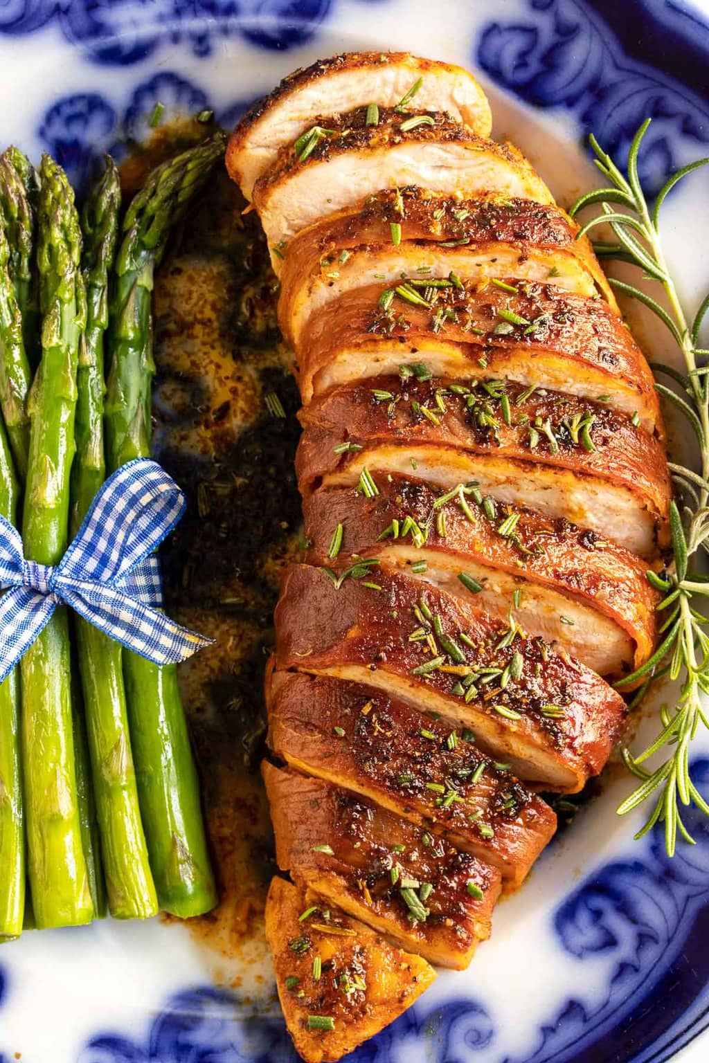 Overhead vertical closeup photo of Prosciutto-Wrapped Chicken Breasts next to a serving of asparagus spears on a Flo blue dinner plate.