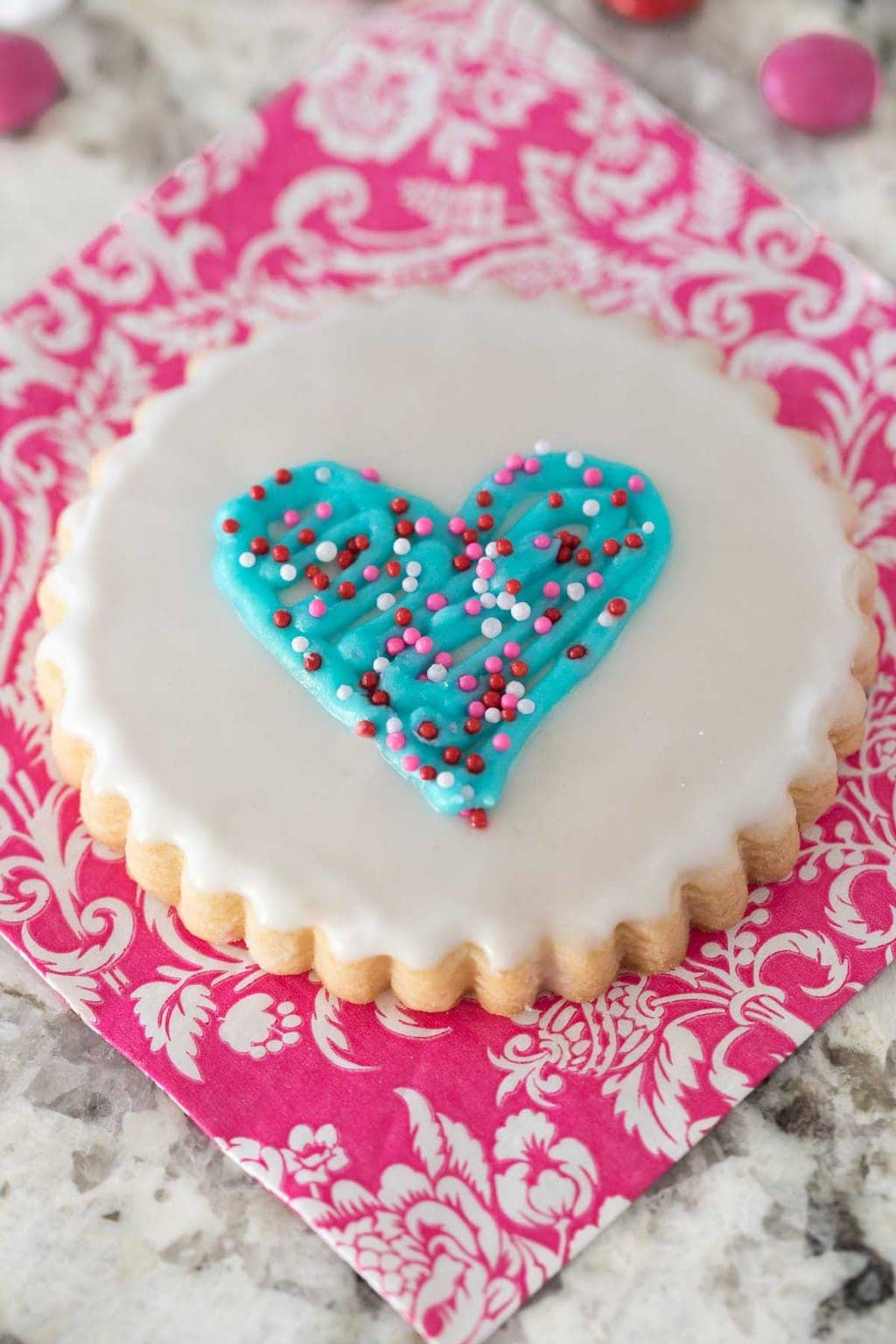 Overhead vertical photo of Easy Decorated Shortbread Cookies on a pink and white patterned napkin.