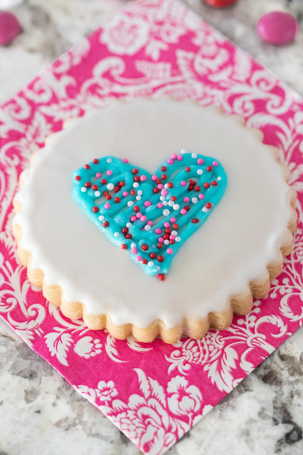 Overhead closeup photo of an Easy Decorated Valentine Cookie on a pink and white patterned napkin.