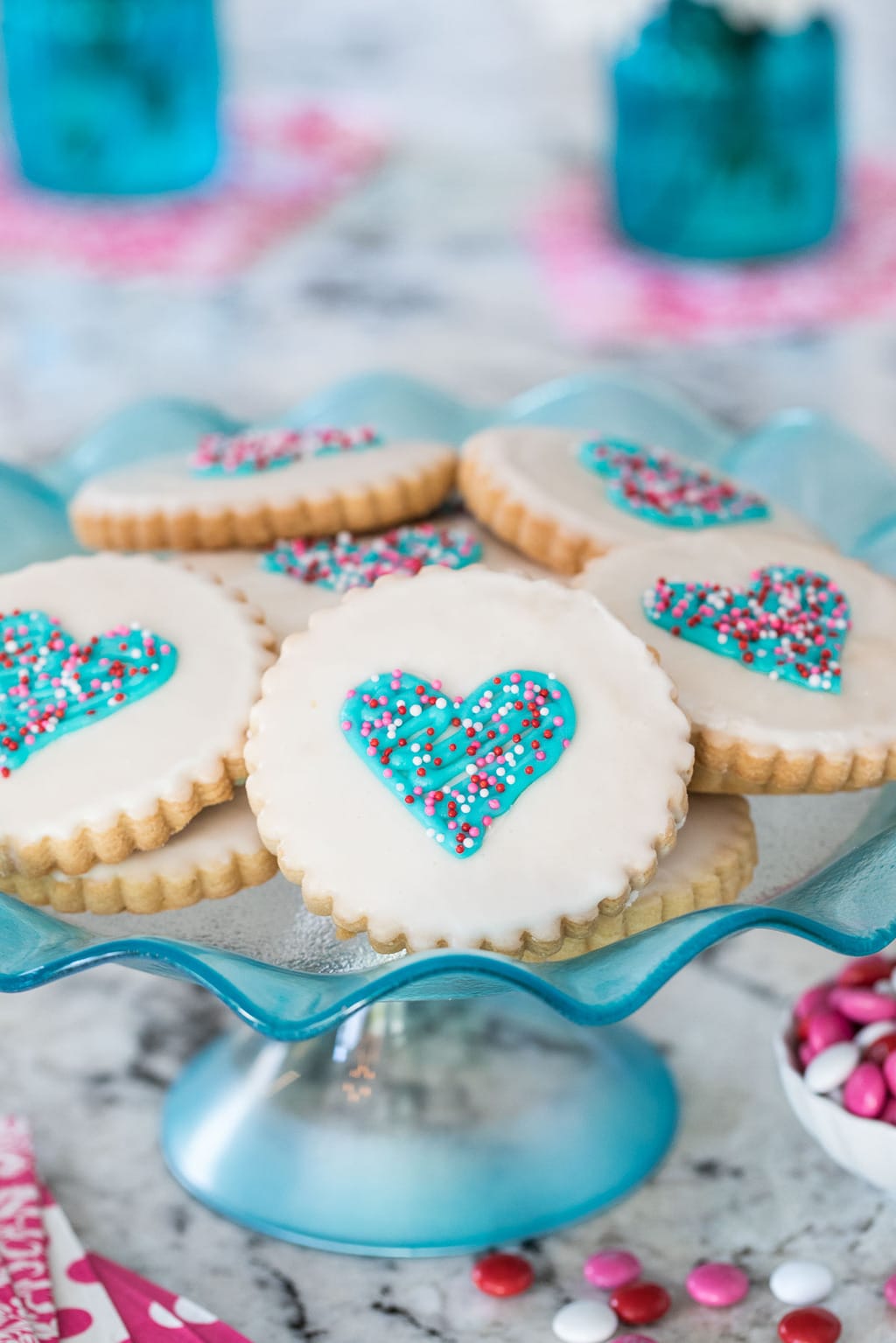 Vertical photo of decorated Easy Decorated Valentine Shortbread Cookies on a blue cake stand.