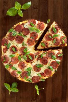 Overhead picture of deep dish pepperoni pizza on a wooden cutting board