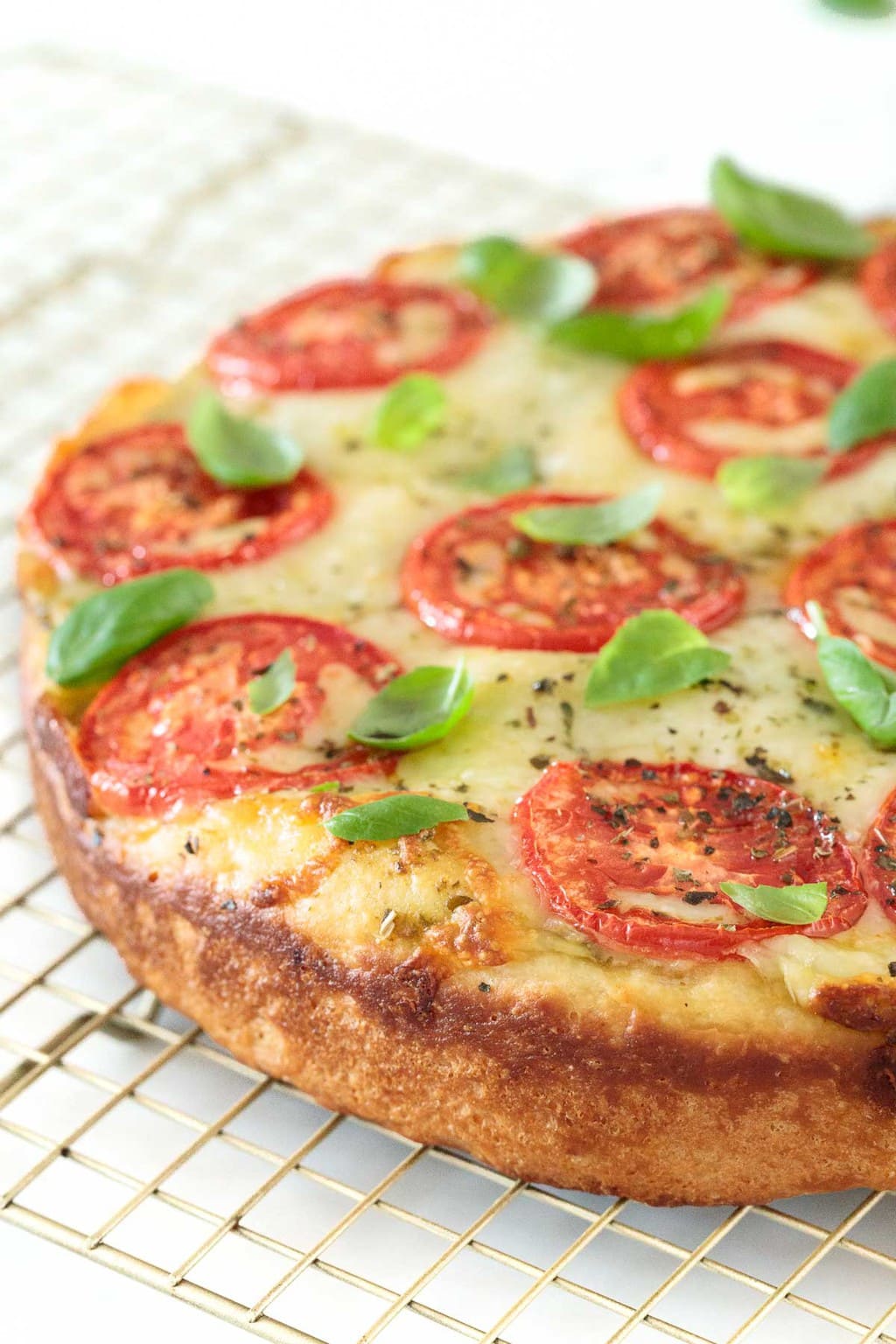 Vertical closeup photo of a Deep Dish Pizza Margherita on a cooling rack.