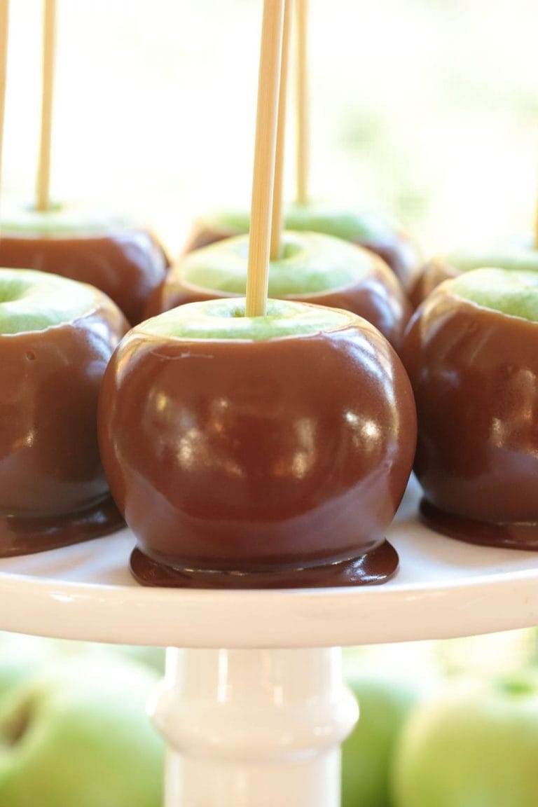 Vertical picture of homemade caramel apples on a white cake stand