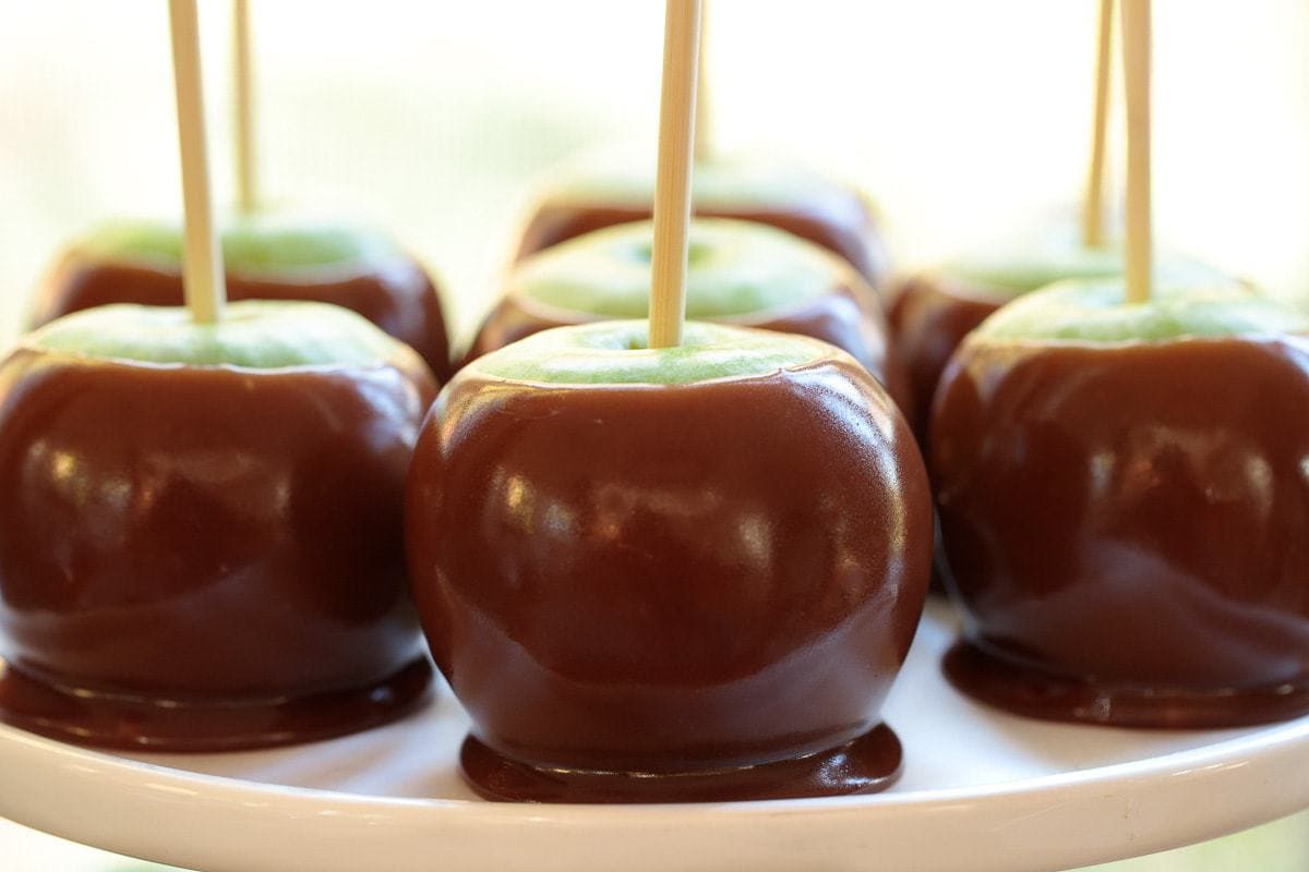 Horizontal photo of a white serving plate filled with Easy Homemade Caramel Apples.