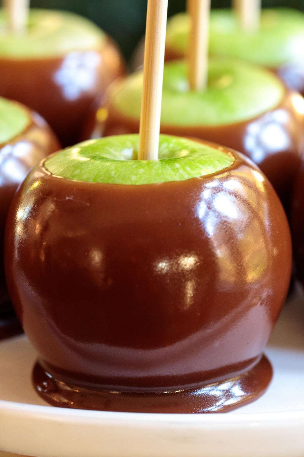 Photo of a white serving plate of Easy Homemade Caramel Apples.