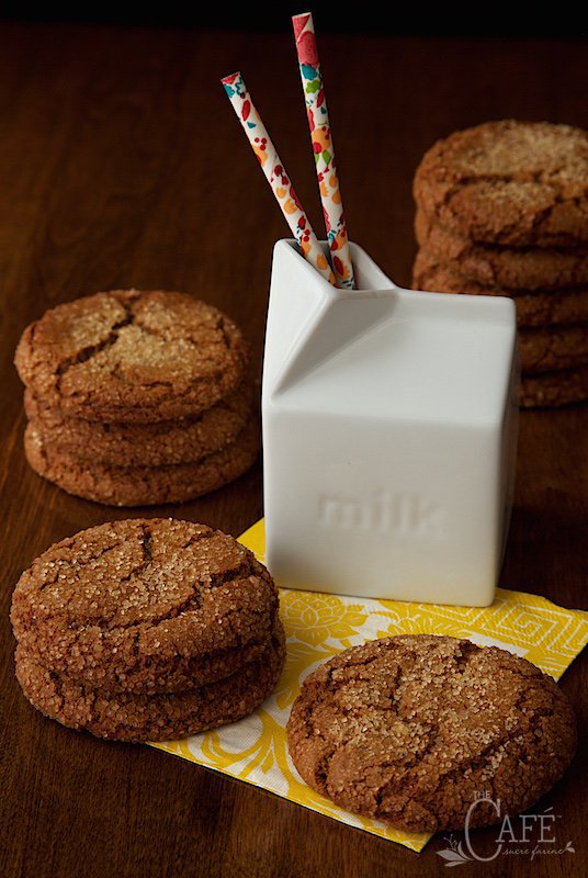 Vertical picture of Easy Bakery-Style Molasses Cookies stacked on a yellow napkin with a carton of milk