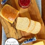 Vertical overhead photo of a loaf of Overnight No-Knead Brioche Bread surrounded by a jar of raspberry jam and Irish butter.