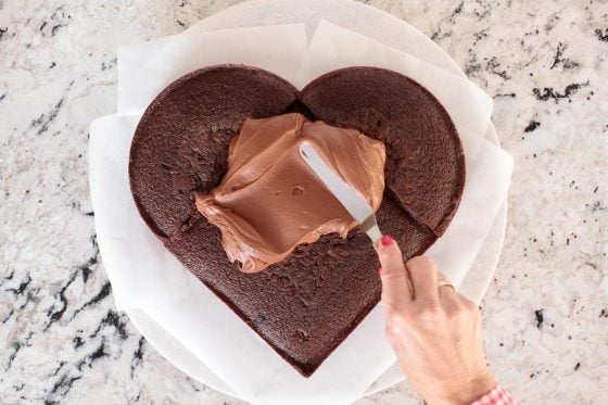 Overhead horizontal process photo of how to ice a Ridiculously Easy One-Bowl Chocolate Heart Cake.