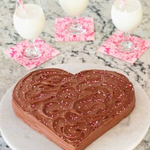 Vertical picture of a chocolate heart cake with glasses of milk