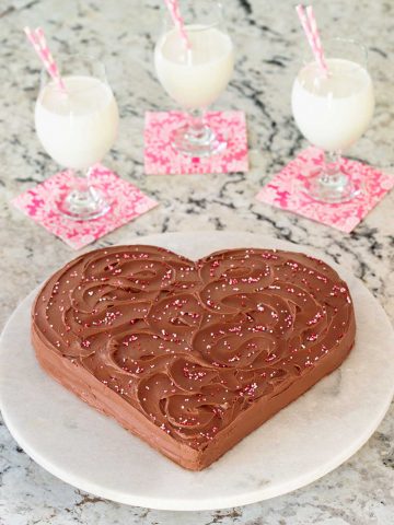 Vertical picture of a chocolate heart cake with glasses of milk