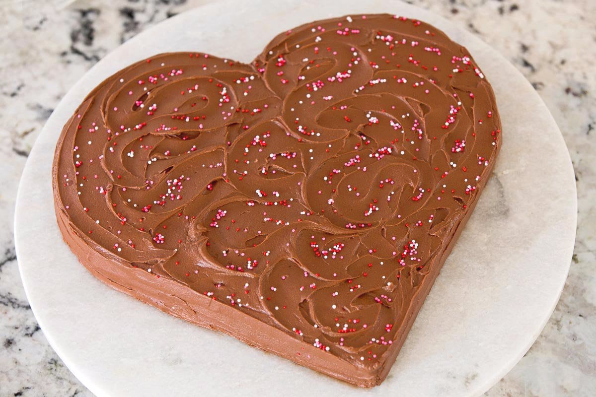 Horizontal photo of a Ridiculously Easy One-Bowl Chocolate Heart Cake on a round marble cake stand.