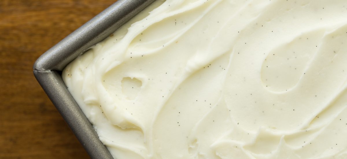 Overhead photo of a pan of Easy Gingerbread Cake with Vanilla Bean Icing on a wood table.
