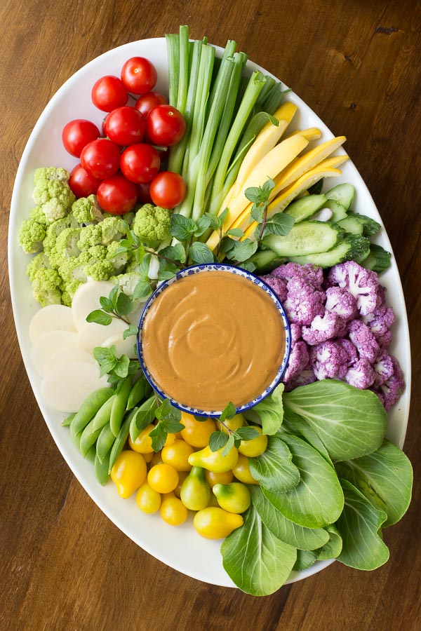 Over head view of a platter of fresh vegetables and peanut sauce