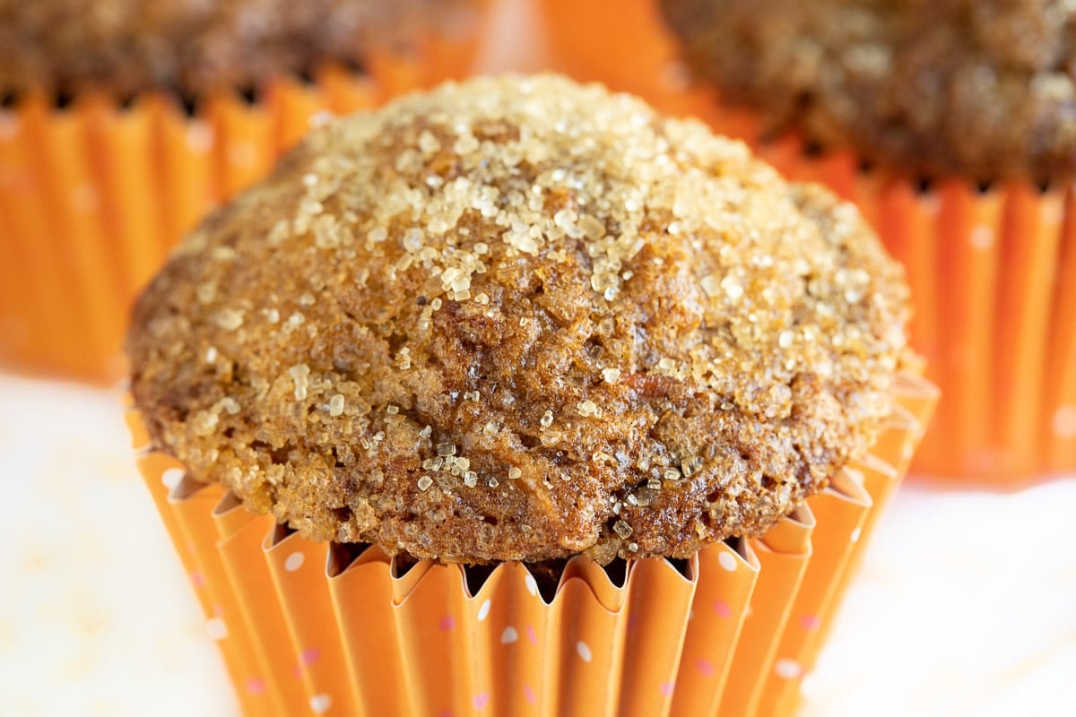 Horizontal extreme closeup photo of Sugar Top Carrot Muffins in orange cupcake liners.