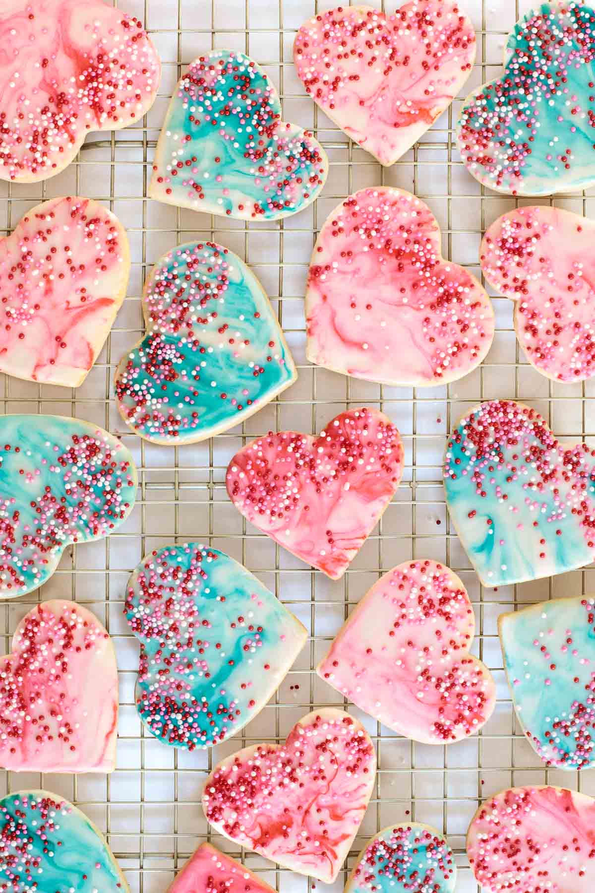 A photo of a batch of Easy Valentine Cookies resting on a gold cooling rack on a white background.