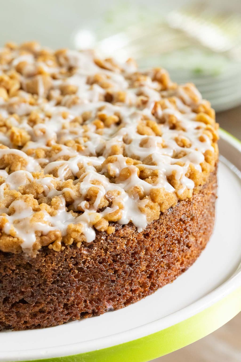 Vertical closeup photo of Easy Zucchini Crumb Cake on a white cake stand bordered with a lime green ribbon.