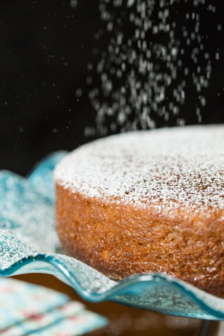 Photo of a Fall Spice Cake with Maple Glaze being sprinkled with powdered sugar.
