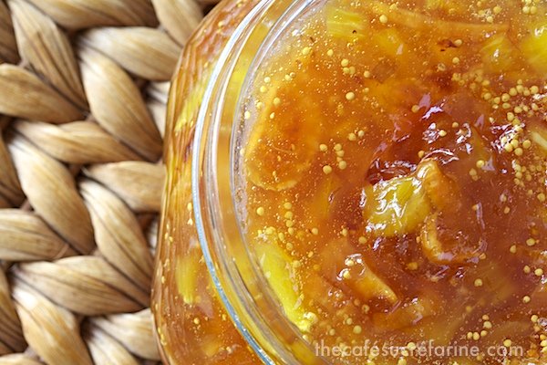 Extreme closeup photo of a glass dish of Fig and Fresh Pineapple Freezer Jam on a wicker table.
