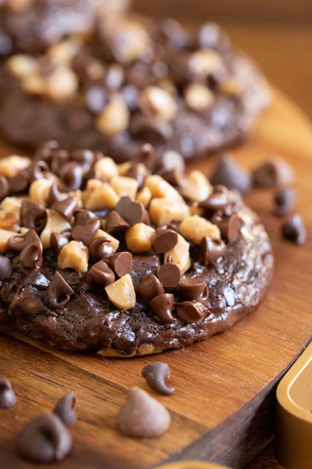 Vertical closeup photo of a batch of Flourless Toffee Chocolate Cookies on a wood serving platter.