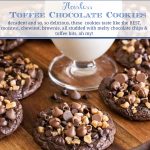 Vertical closeup photo of a batch of Flourless Toffee Chocolate Cookies on a wood serving board with a glass of milk in the center.