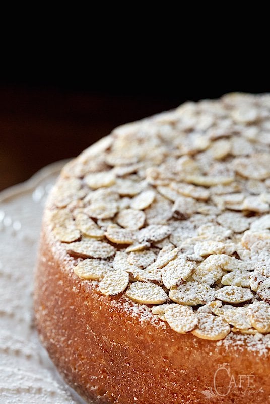 Vertical closeup photo of a French Almond Cake in front of a black background.