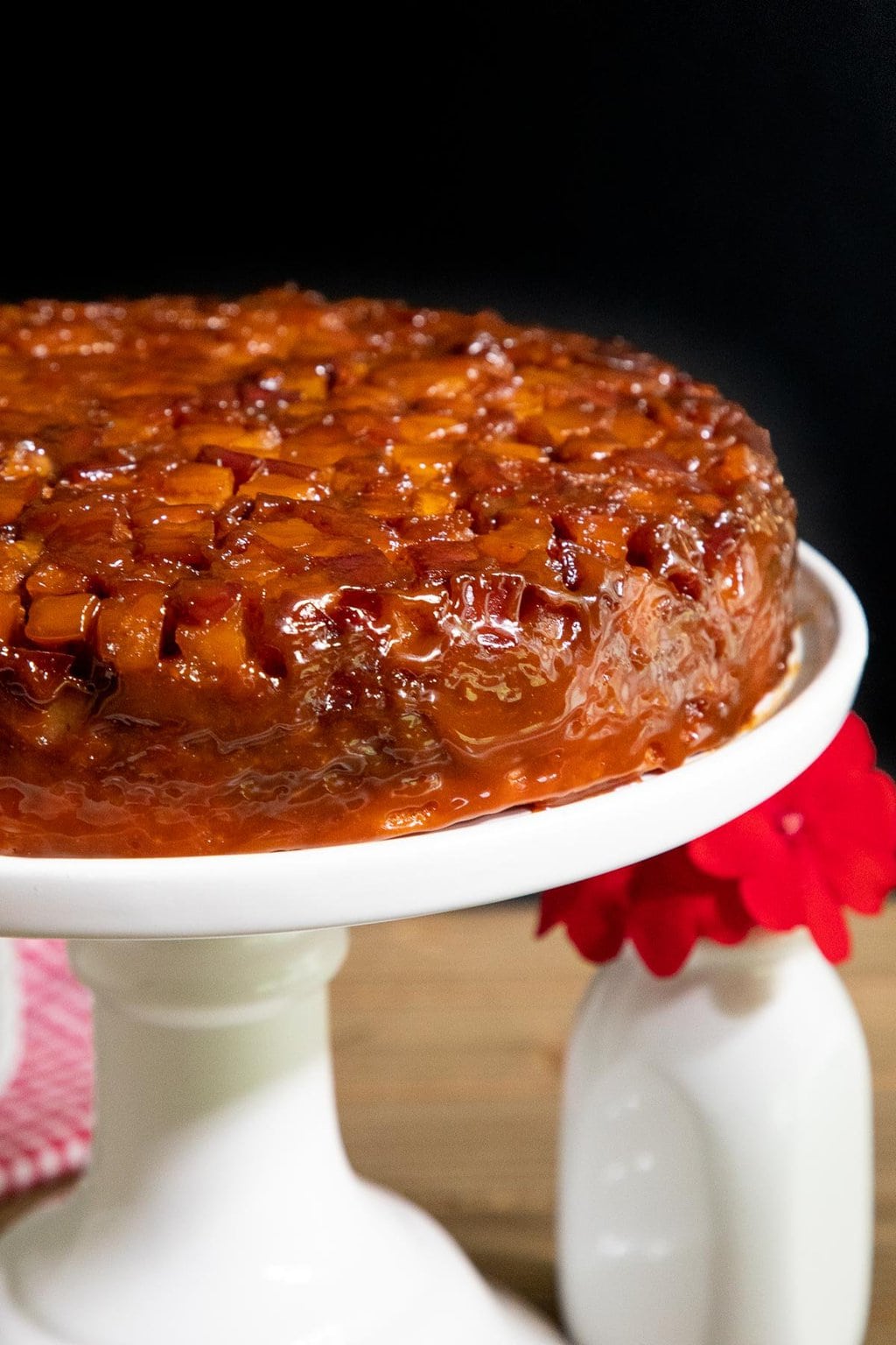 Vertical closeup photo of a French Caramel Apple Cake on a white pedestal cake stand.