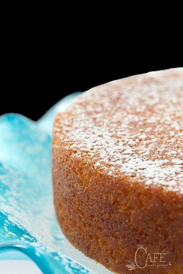 Closeup vertical photo of a French Grandmother's Lemon Yogurt Cake on a turquoise glass ruffled cake stand.
