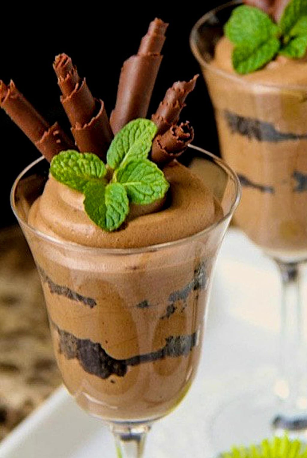 Closeup photo of Chocolate French Silk desserts in glasses garnished with chocolate curls and fresh mint leaves.