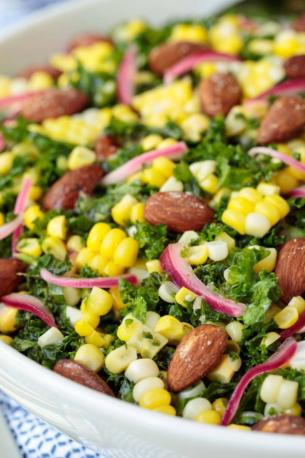 Extreme closeup photo of a white serving bowl of Fresh Corn Kale Salad.