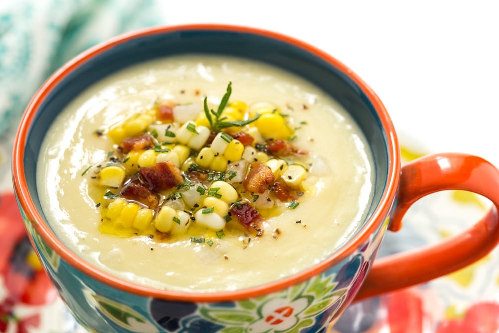 Closeup photo of a cup of Fresh Corn Soup in a brightly decorated bowl.