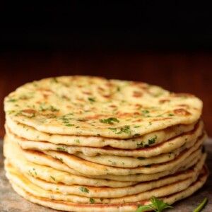 Vertical picture of Greek Yogurt Turkish Flatbread (Bazlama) stacked on a cutting board