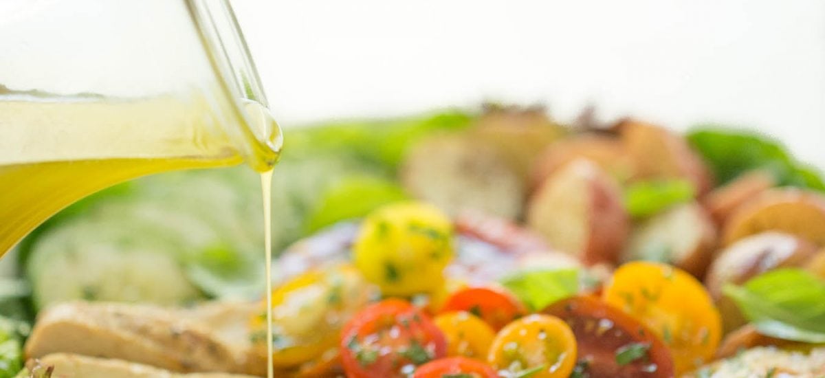 A pour shot of a Grilled Chicken Tomato Cucumber Salad and a bottle of dressing.