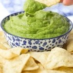 Vertical picture of Guasacaca (Venezuelan Guacamole ) in a blue and white bowl with chips