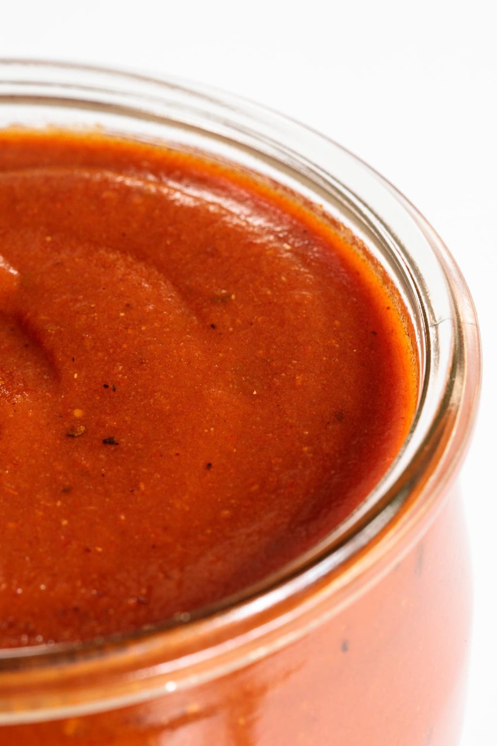 Extreme closeup photo of a glass jar of 10-Minute Homemade Enchilada Sauce.