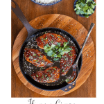 Vertical overhead photo of a skillet of Honey Ginger Indonesian Chicken surrounded by bowls of rice and fresh cilantro